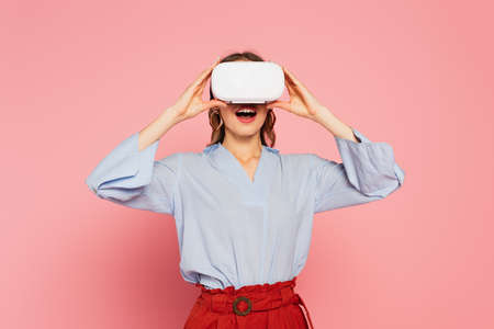 Amazed woman gaming in virtual reality headset on pink backgroundの写真素材
