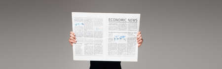 man covering face while reading economic news on gray, bannerの写真素材