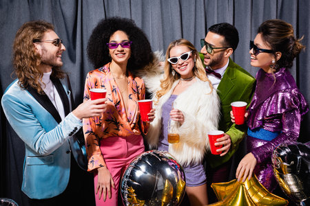 smiling interracial friends in sunglasses standing on gray backgroundの写真素材