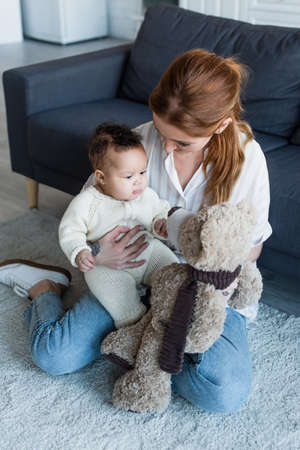 woman sitting on floor with african american baby girl and teddy bearの写真素材