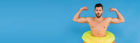Muscular man in inflatable rings showing muscles isolated on blue, bannerの写真素材