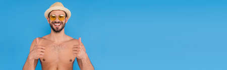 Shirtless man in sunglasses showing thumbs up isolated on blue, bannerの写真素材