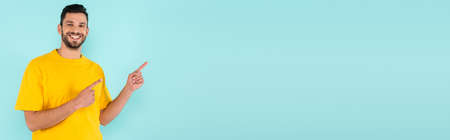 Smiling man pointing with fingers isolated on blue, bannerの写真素材