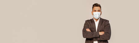 young man in medical mask standing with crossed arms isolated on gray with lilac shade, bannerの写真素材