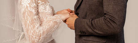 partial view of bride and groom holding hands isolated on gray, bannerの写真素材