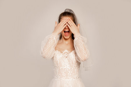 excited bride covering eyes with hands isolated on gray with lilac shadeの写真素材