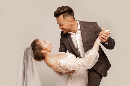 elegant couple of newlyweds dancing isolated on gray with lilac shade