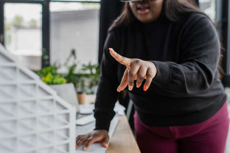 cropped view of blurred african american plus size woman pointing at blurred carton house modelの写真素材