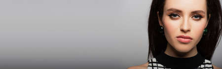 close up of young woman in headband and earrings isolated on gray, banner