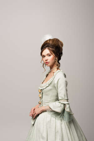 young woman in elegant vintage dress looking at camera isolated on gray