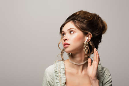 dreamy vintage style woman listening music in wireless earphone isolated on gray