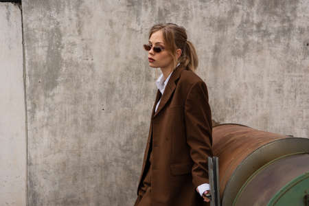 dreamy young model in stylish sunglasses and trendy suit posing on rooftopの写真素材