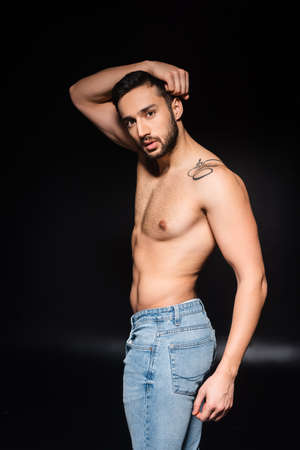 Shirtless man in jeans posing on black background