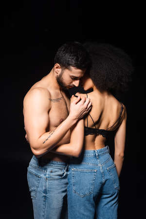 Interracial couple in jeans hugging isolated on blackの写真素材