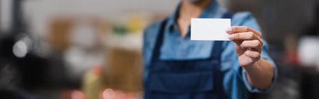 close up view of empty card in hand of blurred young african american mechanic in garage, bannerの写真素材