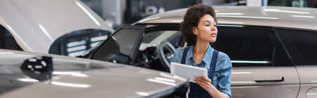 young african american mechanic working with digital tablet in garage, banner