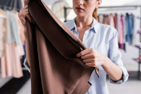Cropped view of fabric in hands of blurred seamstressの写真素材