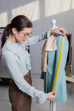 Seamstress measuring sleeve of jacket on mannequinの写真素材