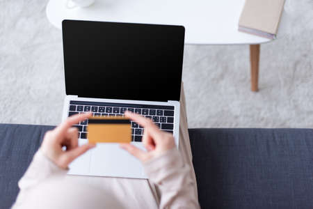 overhead view of muslim woman holding credit card near laptop with blank screenの写真素材