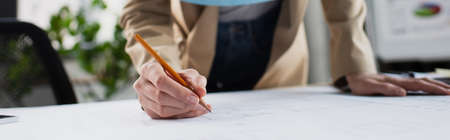 partial view of engineer drawing blueprint in office, banner