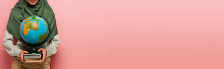 partial view of muslim teacher with globe and books on pink background, bannerの写真素材