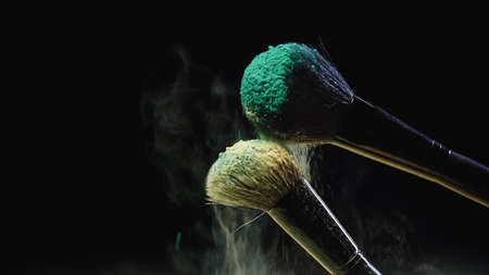 cosmetic brushes with blue and yellow powder on blackの写真素材