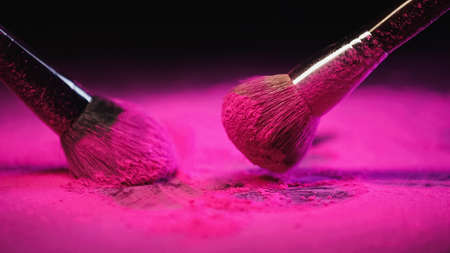 messy cosmetic brushes near bright pink powder on black backgroundの写真素材