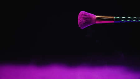 cosmetic brush with purple holi paint on black backgroundの写真素材