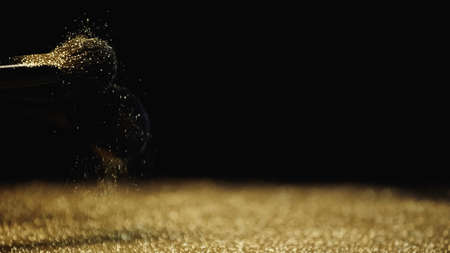cosmetic brushes with shiny golden sparkles on black backgroundの写真素材