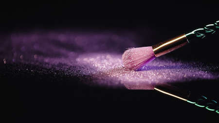 soft cosmetic brush near dust with sparkling pink glitter on blackの写真素材