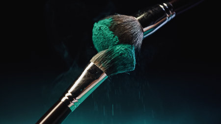cosmetic brushes with vibrant turquoise holi paint near dust on black backgroundの写真素材