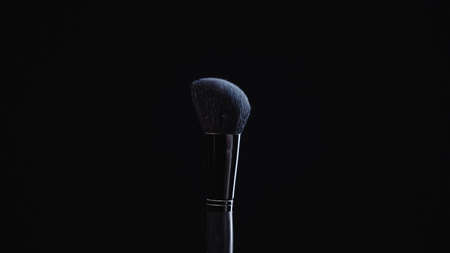 soft cosmetic brush with blue powder isolated on blackの写真素材