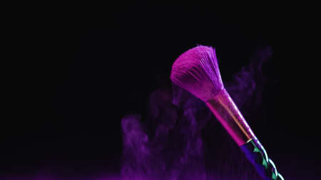 cosmetic brush with purple powder near falling dust on black backgroundの写真素材
