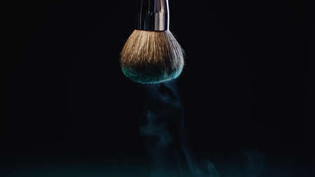 blue dust falling down from soft cosmetic brush on blackの写真素材