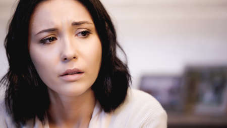 portrait of depressed brunette woman in beige sweater at homeの写真素材
