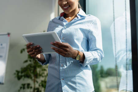 Cropped view of smiling african american businesswoman with digital tablet in office