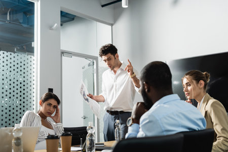 businessman with newspaper showing idea gesture near multiethnic coworkers