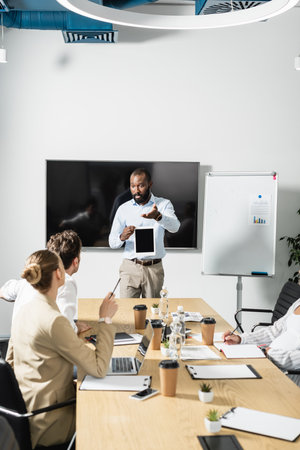african american businessman with digital tablet pointing with hand during meetingの写真素材