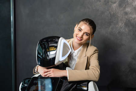 businesswoman smiling at camera while embracing robot in office