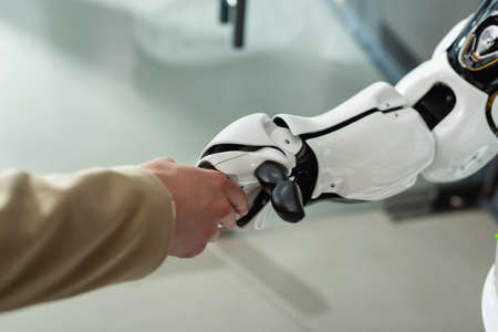partial view of businesswoman shaking hands with robot in officeの写真素材