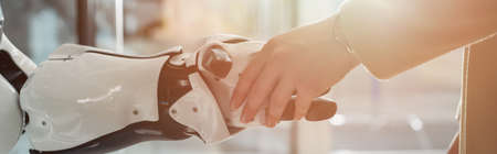 cropped view of businesswoman shaking hand with robot, banner