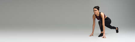 sportswoman in low start position on gray background, banner