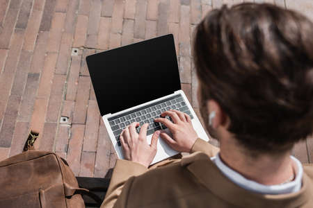 high angle view of blurred businessman typing on laptop with blank screen