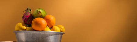 exotic fruits in metal bowl on orange background, bannerの写真素材