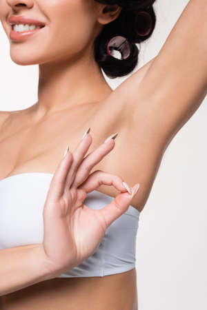 partial view of young woman with smooth armpit showing okay gesture isolated on white
