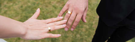 Cropped view of rings on fingers of newlyweds outdoors, bannerの写真素材