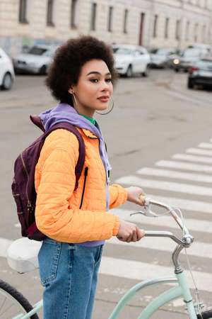 African american woman with bike looking away near blurred crosswalk outdoorsの写真素材