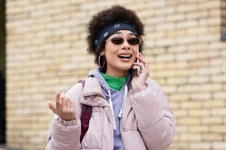 Happy african american woman in sunglasses talking on smartphone outdoors