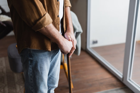Cropped view of senior man holding crutch at homeの写真素材