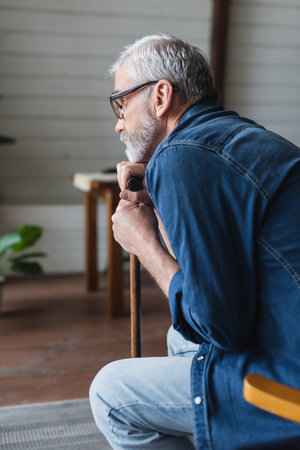 Side view of lonely pensioner holding crutch at homeの写真素材